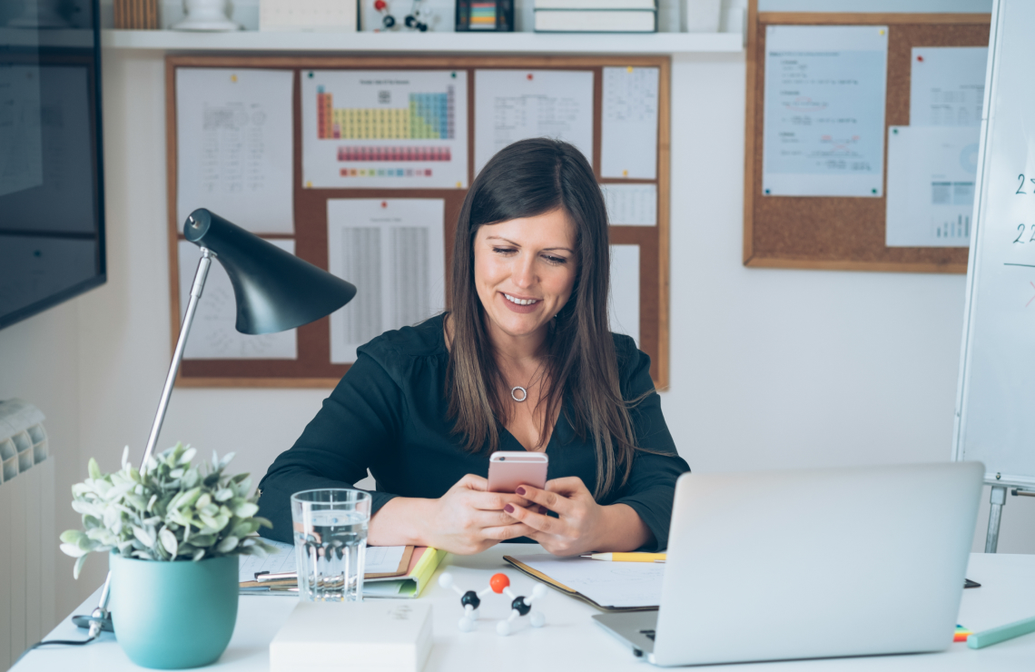 teacher in class smiling and looking at phone