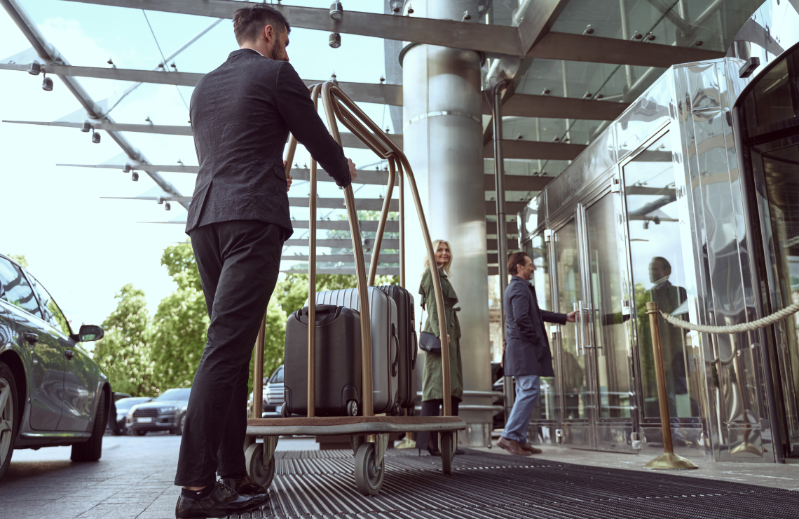 male hospitality professional taking suitcases into hotel